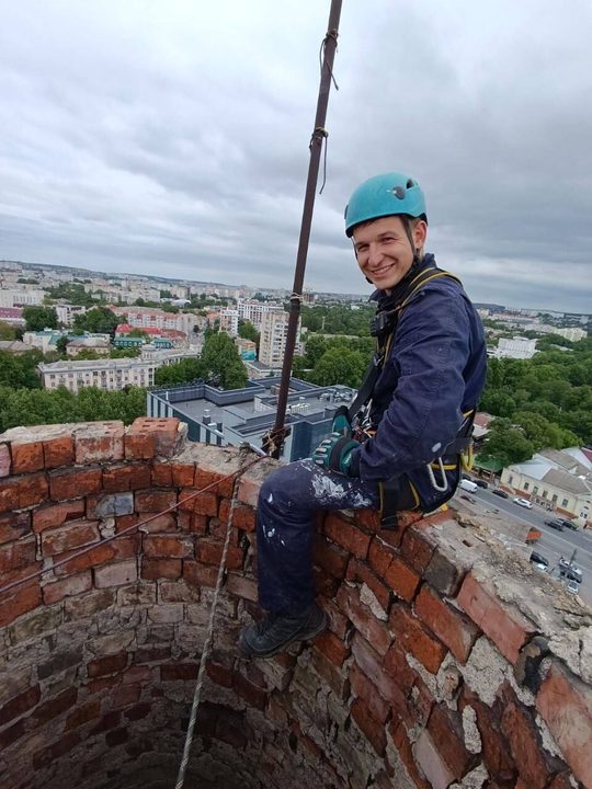 Альпинист у кирпичной кладки на высоте