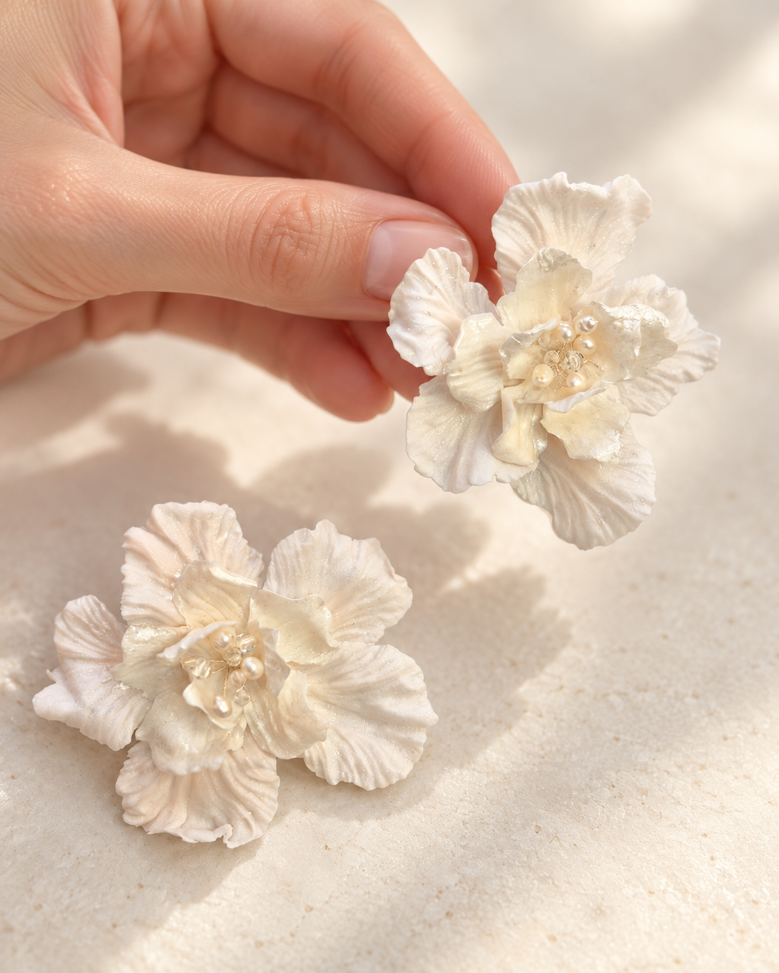 White flower earrings held in a hand