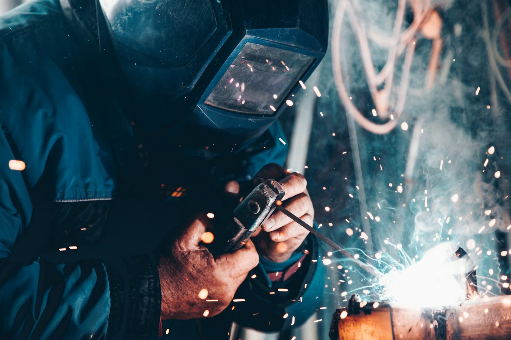 Welder cutting and welding metal with sparks